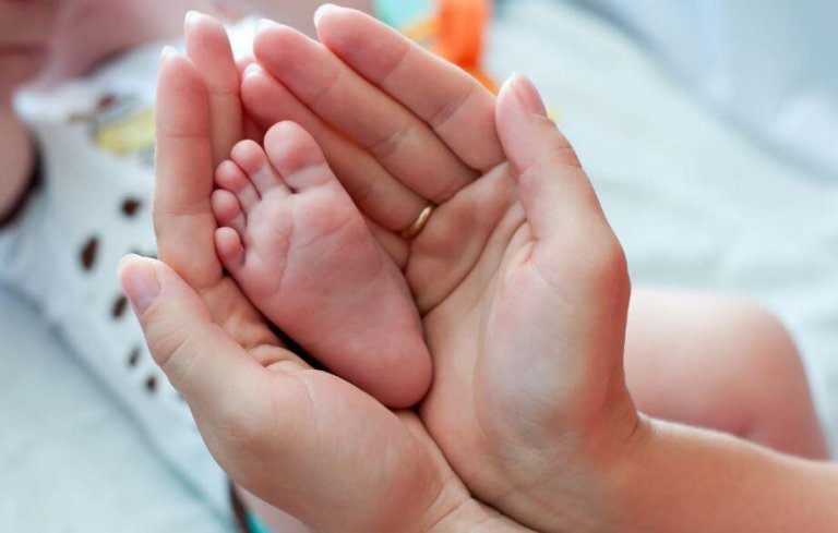 ellerinin arasında bebeğinin ayağını tutan anne