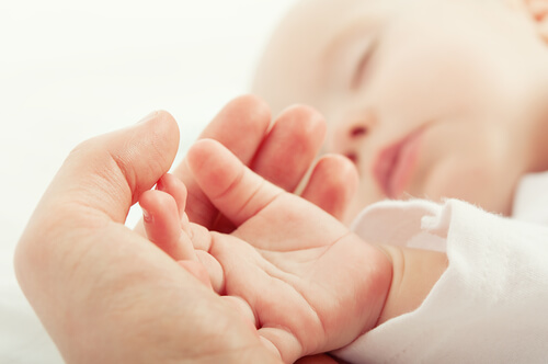 elinde bebeğinin elini tutan anne ve uyuyan bebeği