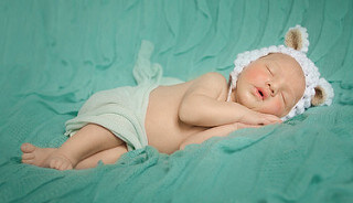 yeşil fonda uyuyan beyaz bereli bebek