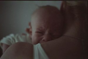 ağlayan bebeğini tutan anne