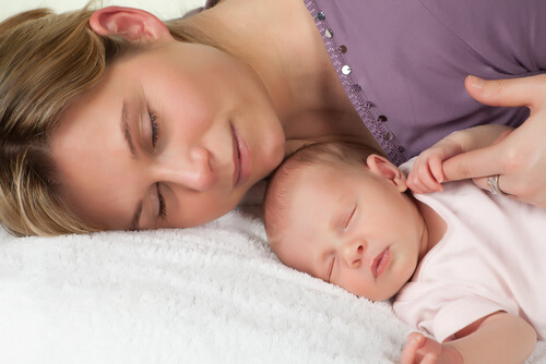 uyurken annesinin parmağını tutan bebek
