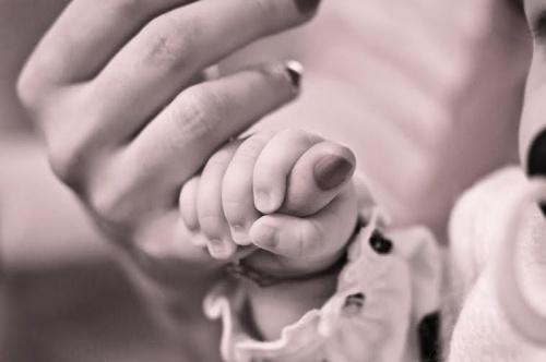 annesinin parmağını tutan bebek