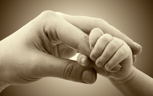 annesinin parmağını tutan bebek eli