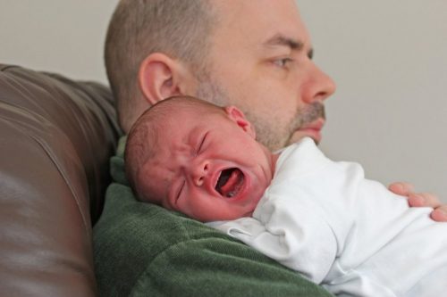 babasının kucağında ağlayan bebek