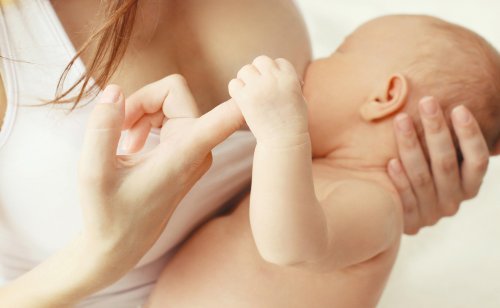 annesinin parmağını tutarak emen bebek
