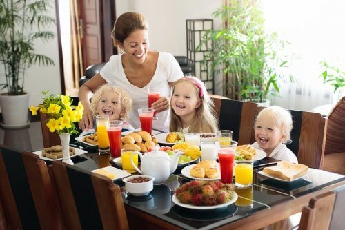 anne ve üç çocuk masada oturuyorlar sonbaharda önerilen vitaminler
