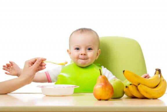 yeşil önlüklü mutlu yemek yiyen bebek