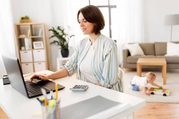 bebeği oyun oynarken ders çalışan anne