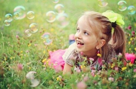 çimde baloncuklarla oynayan kız çocuğu