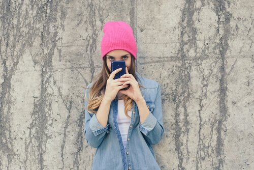 Duvara dayanmış fotoğraf çeken pembe bereli kız