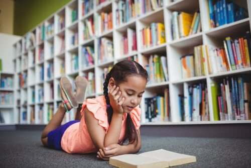 Kütüphanede yatarak kitap okuyan bir kız