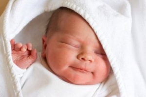 Gülümseyerek kundakta uyuyan bebek