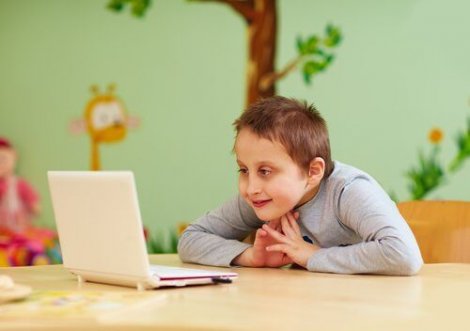 Gülümseyerek bilgisayara bakan çocuk