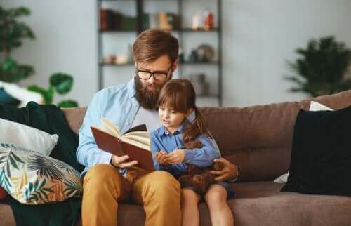 Kanepede babasıyla sarılarak kitap okuyan kız