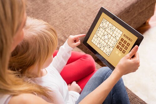 Çocuğu kucağında sudoku oynayan anne