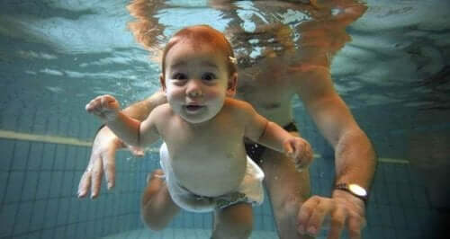 Babasıyla havuzda yüzen bir bebek