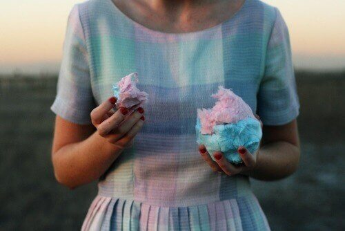 Yediği pamuk şekerle aynı tonda pembe ve mavi elbise giyen kadın