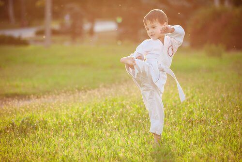 Çimenlikte dövüş sporu yapan küçük erkek çocuk
