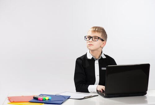 Bilgisayar başında yan tarafa bakan gözlüklü çocuk