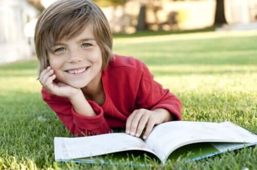Çimlerin üzerinde kitap okuyan bir çocuk