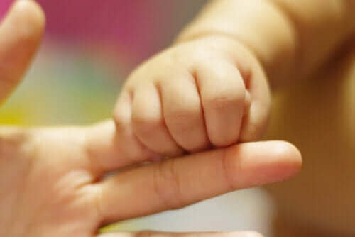 annesinin parmağını tutan bebek
