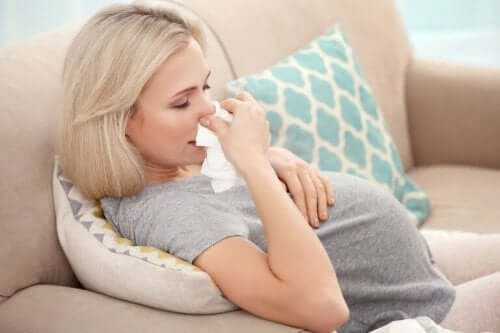 Hamilelikte grip hastalığına yakalanmış gri tişörtlü burnunu silen anne