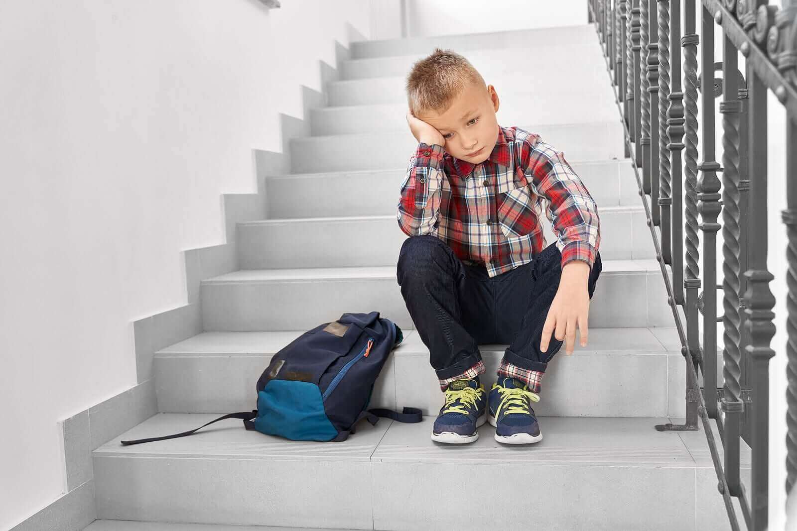 Merdivende yalnız başına oturmuş düşünen çocuk