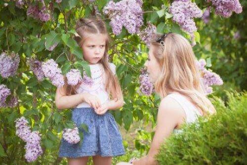 Bahçede çiçekler arasında annesine kızarak bakan kız