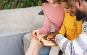 çocukları ile yüksek sesle kitap okuyan anne ve baba