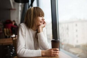 Kahvesini izlerken dışarıyı izleyen genç kız