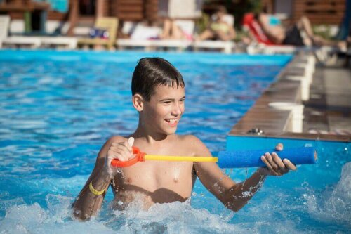 Havuzun içinde su tabancası ile oynayan bir çocuk.