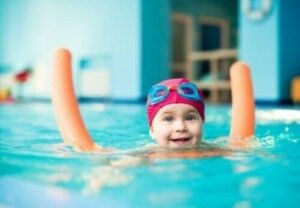 küçük bir çocuk havuzda gülümseyerek yüzüyor