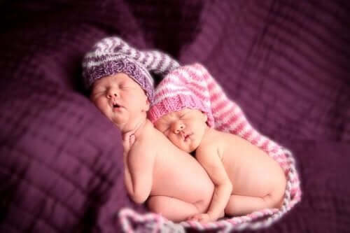 Birbirlerine sarılmış uyuyan ikiz bebekler.