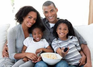 Anne baba ve iki kızı birlikte film izleyip mısır yiyorlar.